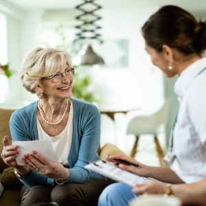 Happy senior woman talking to a nurse during home visit.